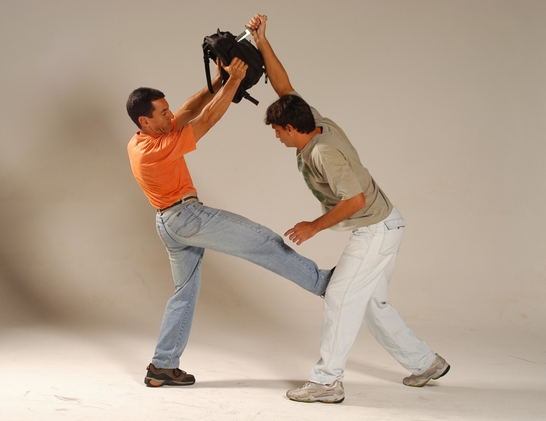 Homem defendendo um ataque de faca com a mochila