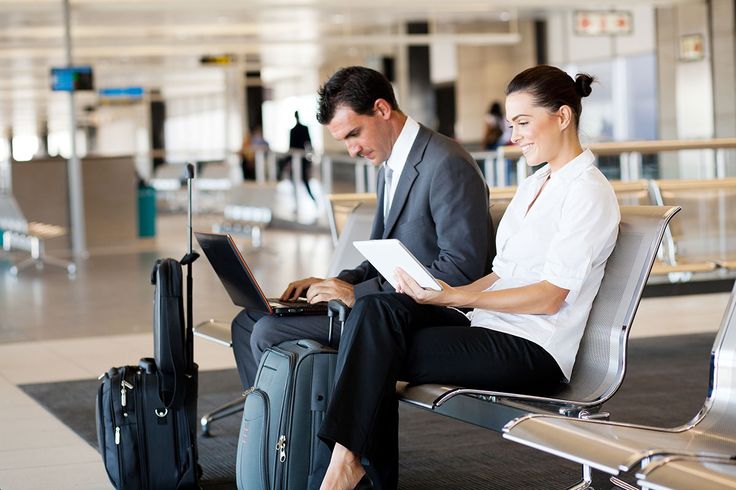 Mulher e homem sentados com notebook no aeroporto