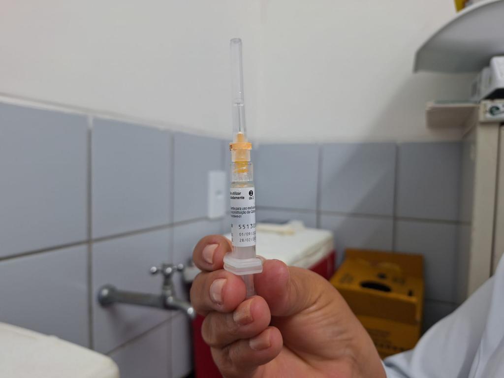 Mão segurando uma vacina