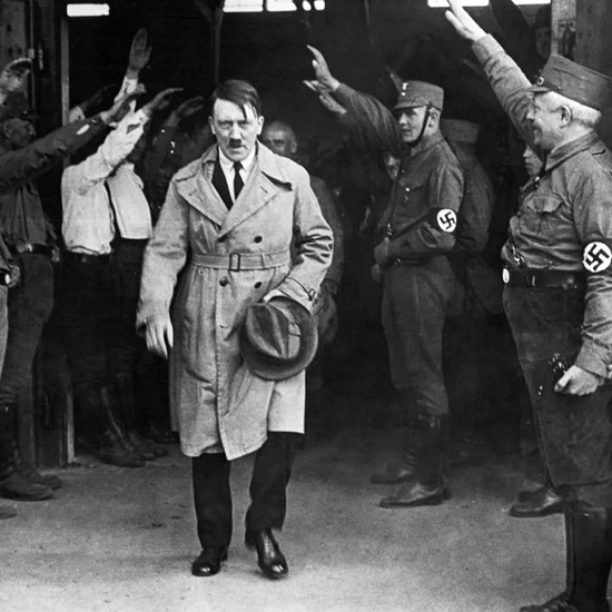 Hitler com chapéu na mão sendo saudado pelos soldados